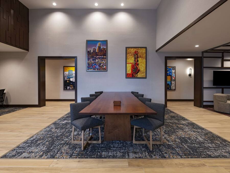 Una sala de conferencias moderna con una mesa de madera, seis sillas y dos cuadros grandes en las paredes.