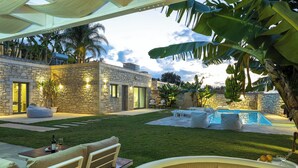 Una casa de piedra con piscina, mobiliario de exterior y una bañera de hidromasaje.