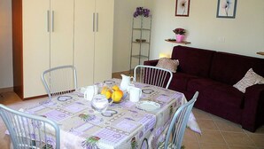 Un coin repas avec une table dressée pour quatre personnes, un canapé et une échelle appuyée contre le mur.