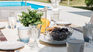 A dining table set outdoors with a pool in the background. - villa Stefano in Moniga del Garda (Moniga del Garda)