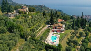 Vue aérienne d’une propriété dotée d’une piscine, d’un bâtiment à toit rouge et d’un paysage montagneux en arrière-plan.