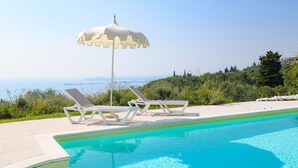 Une piscine avec deux chaises longues blanches et un parasol blanc.