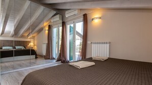 A bedroom with a large bed, a mirror, a radiator, and a window with curtains. - Cà Rossa - Orchidea with stunning lake view (Toscolano-Maderno)