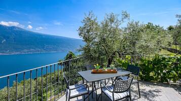Eine Terrasse mit Tisch und Stühlen mit Blick auf einen See und Berge.