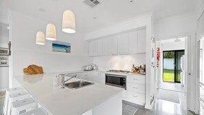 A modern kitchen with white cabinetry, a central island with a sink, and pendant lighting.
