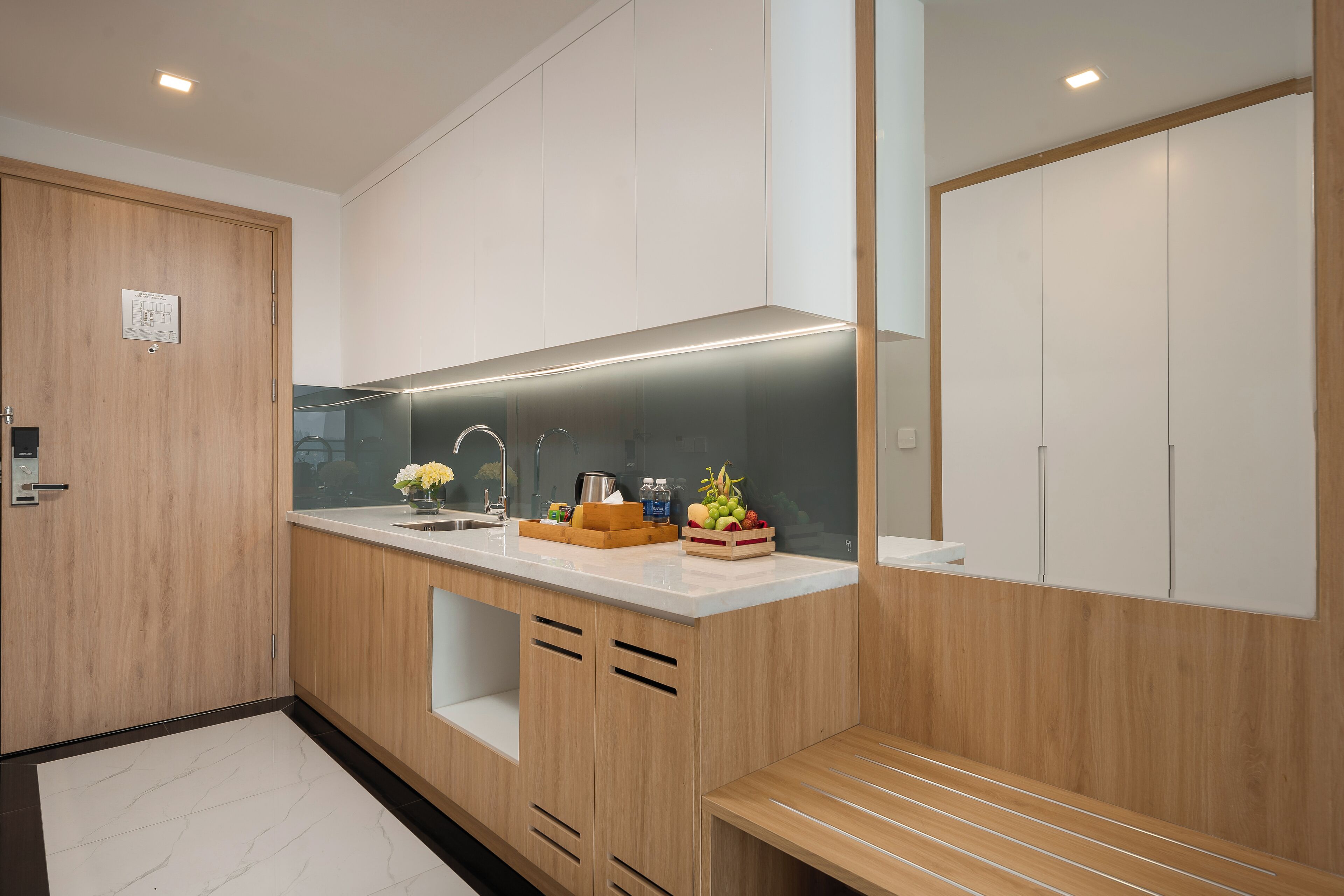 Una cocina moderna con armarios de madera, encimera blanca y horno empotrado.