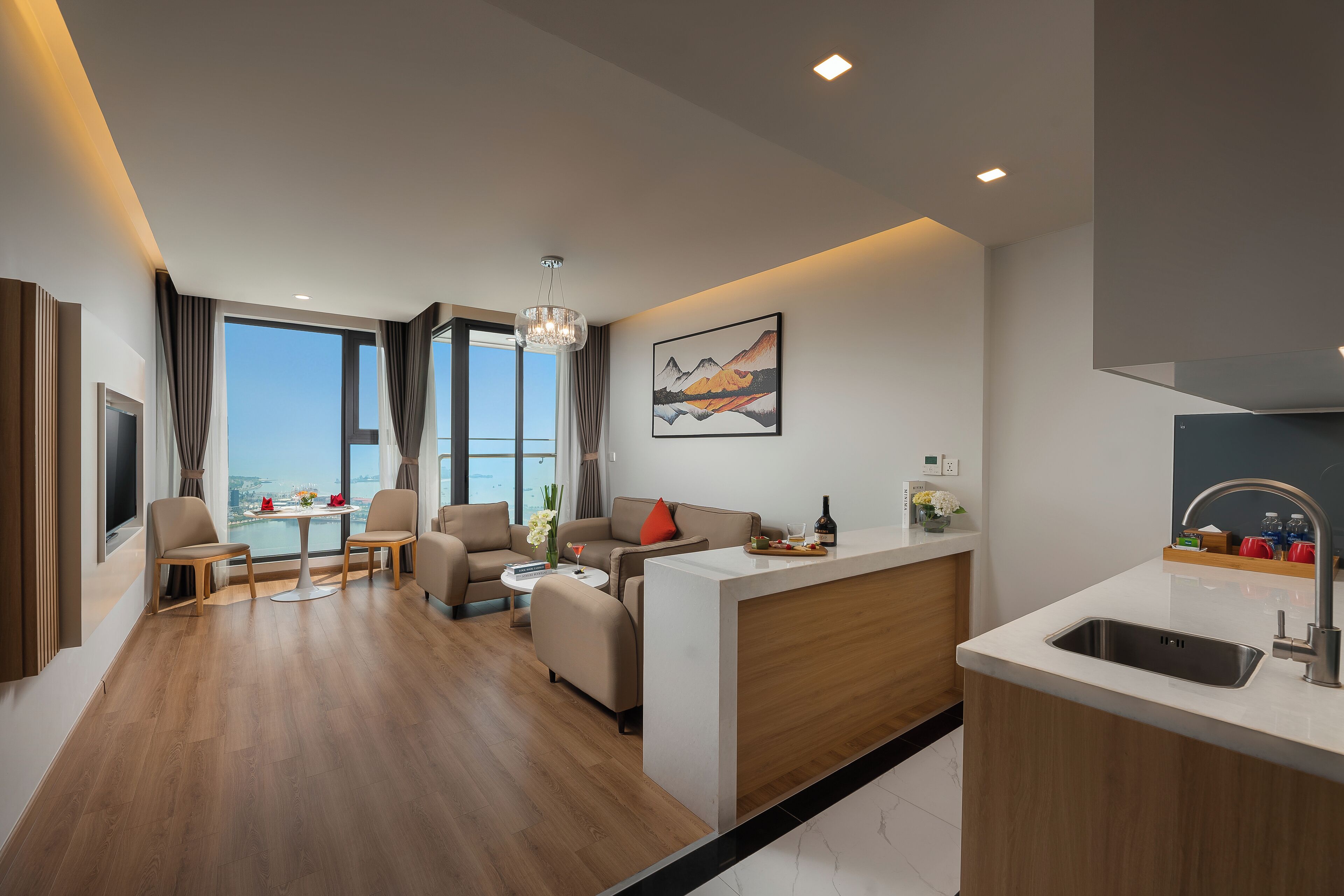 A modern hotel room with a living area, dining space, and a kitchen.