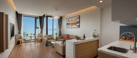 A modern hotel room with a living area, dining space, and a kitchen.