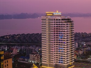 Een hoog hotel met een opvallend bord bovenop, meerdere balkons en een uitzicht op de omliggende woonwijk.