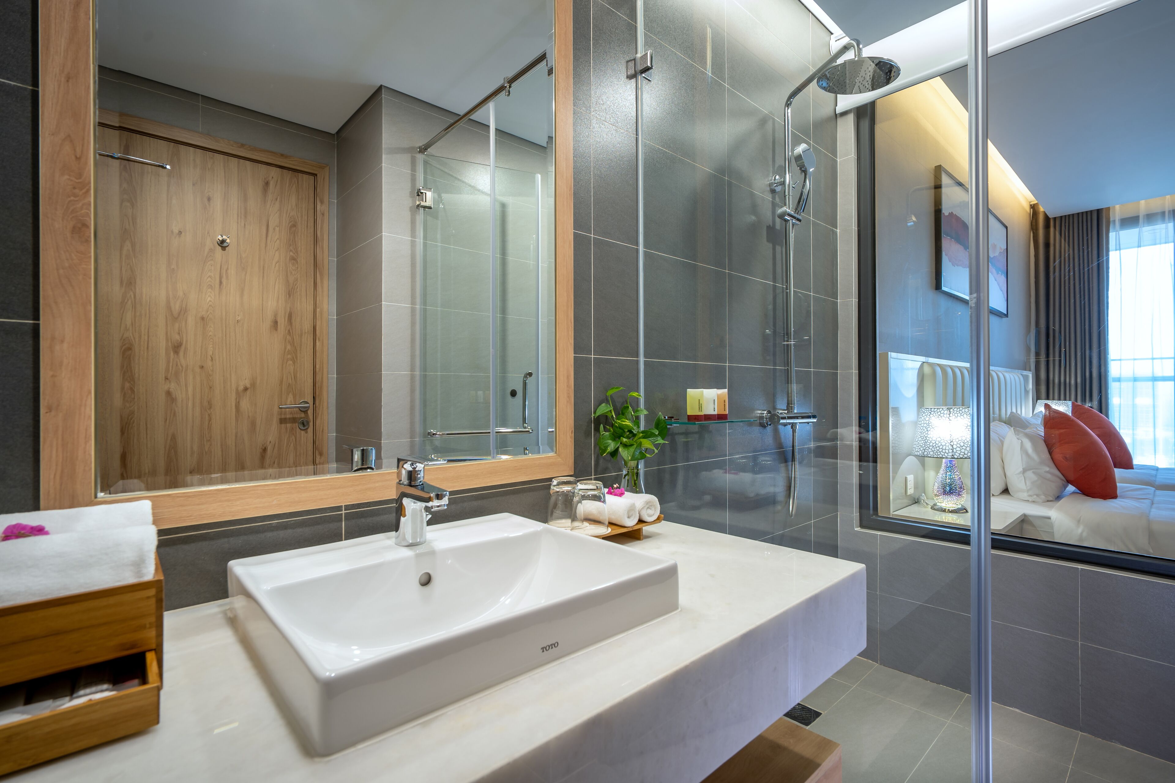 A modern bathroom with a large mirror, a white sink, and a glass shower enclosure.