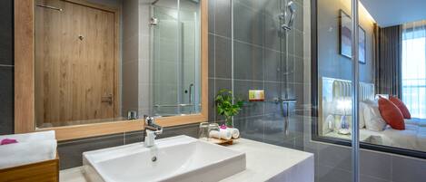 A modern bathroom with a large mirror, a white sink, and a glass shower enclosure.