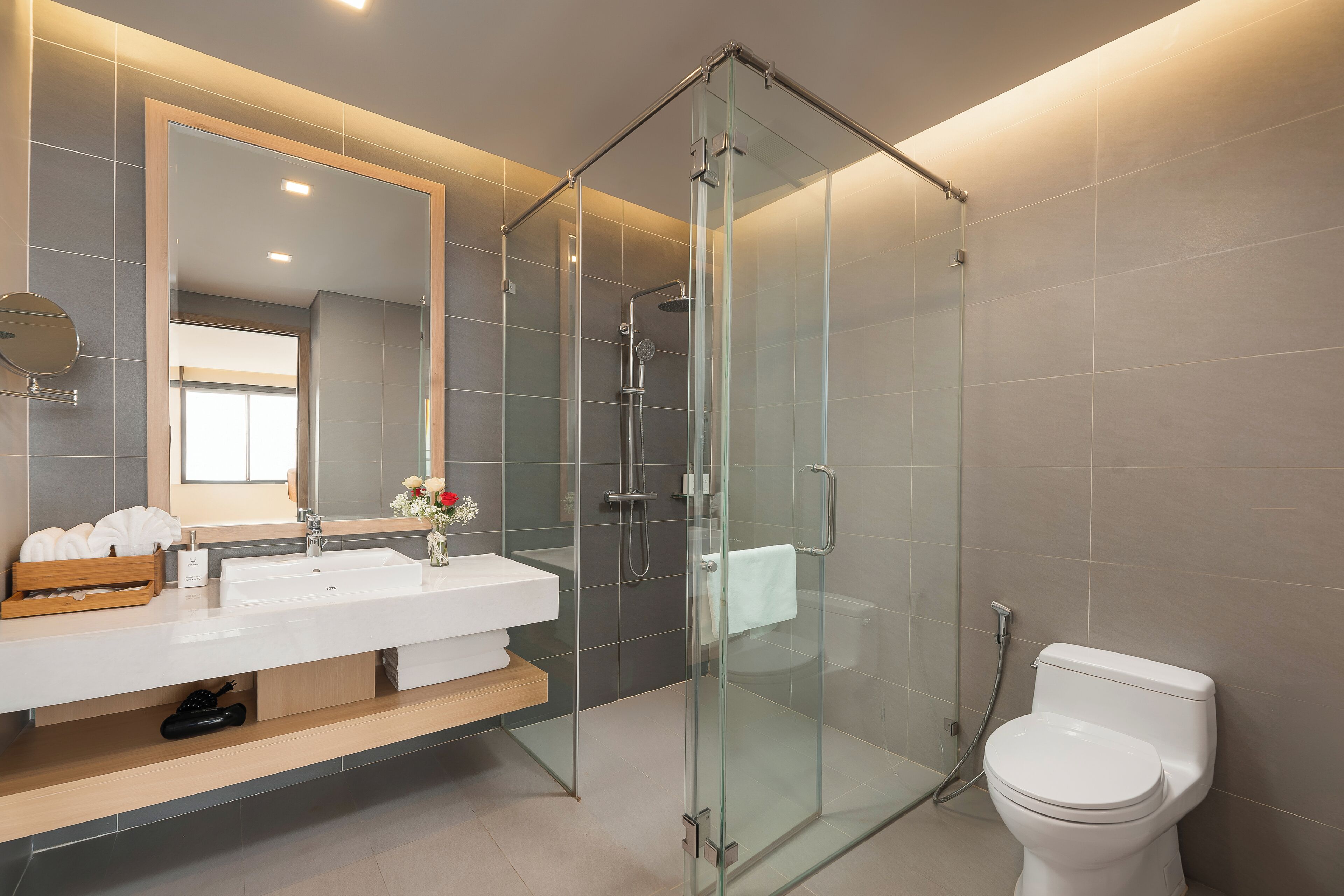A modern bathroom with a glass-enclosed shower, a white sink, and a toilet.