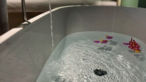 Una bañera con agua corriendo, rodeada de flores.