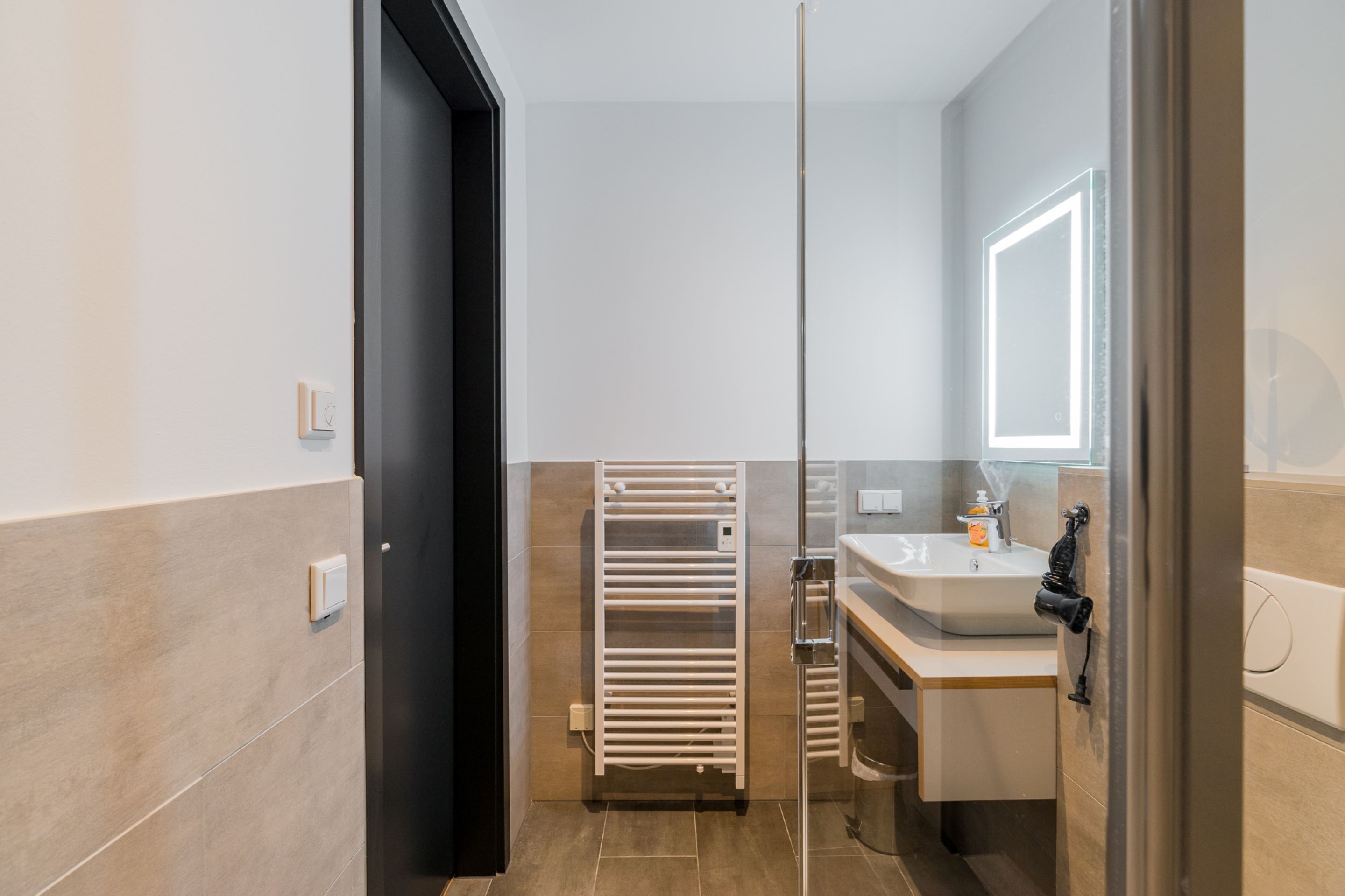 Une salle de bain moderne avec une douche à parois de verre, un porte-serviettes et un lavabo avec un miroir.