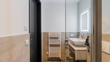 Une salle de bain moderne avec une douche à parois de verre, un porte-serviettes et un lavabo avec un miroir.