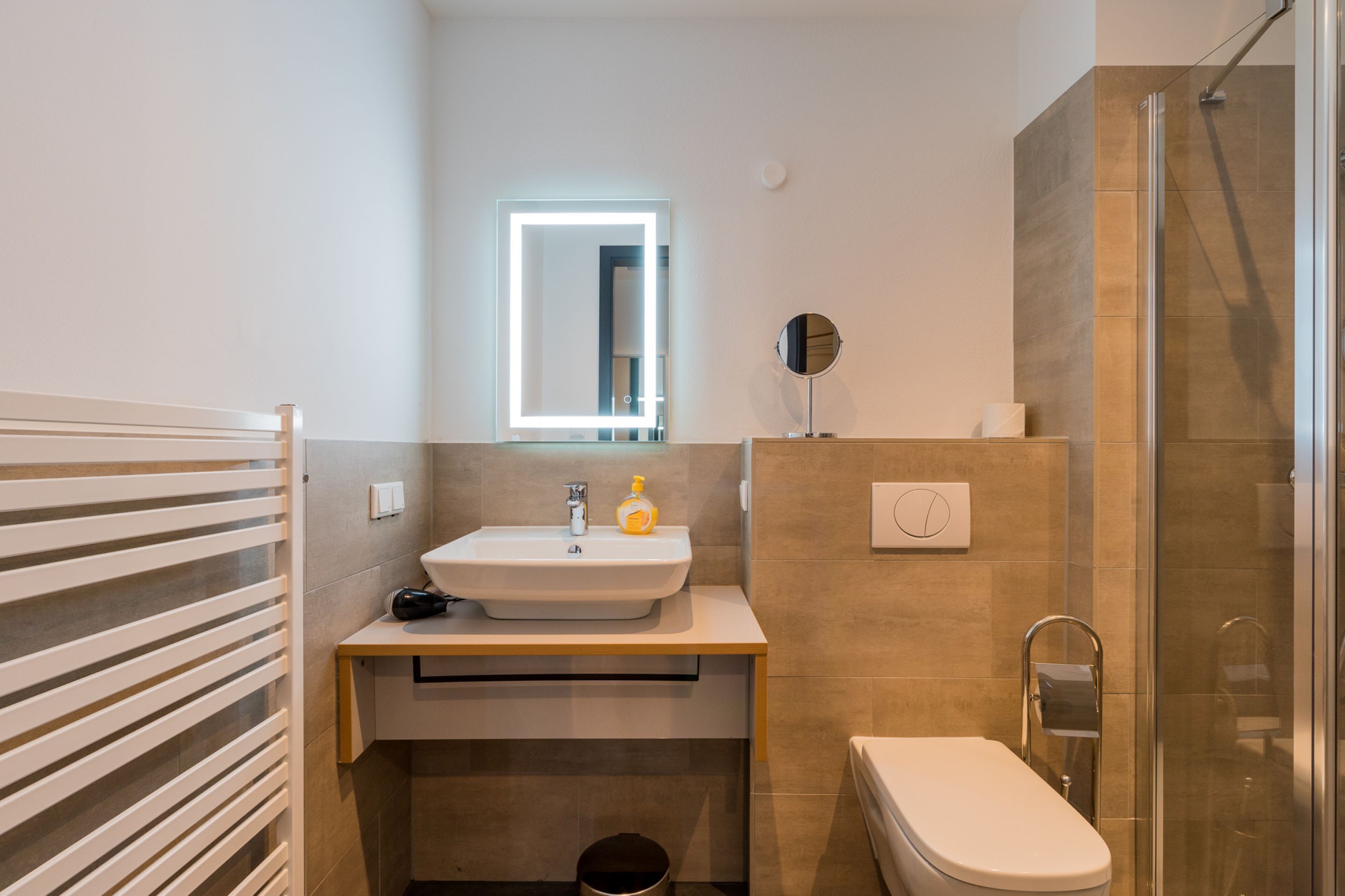 A modern bathroom with a sink, mirror, and toilet.