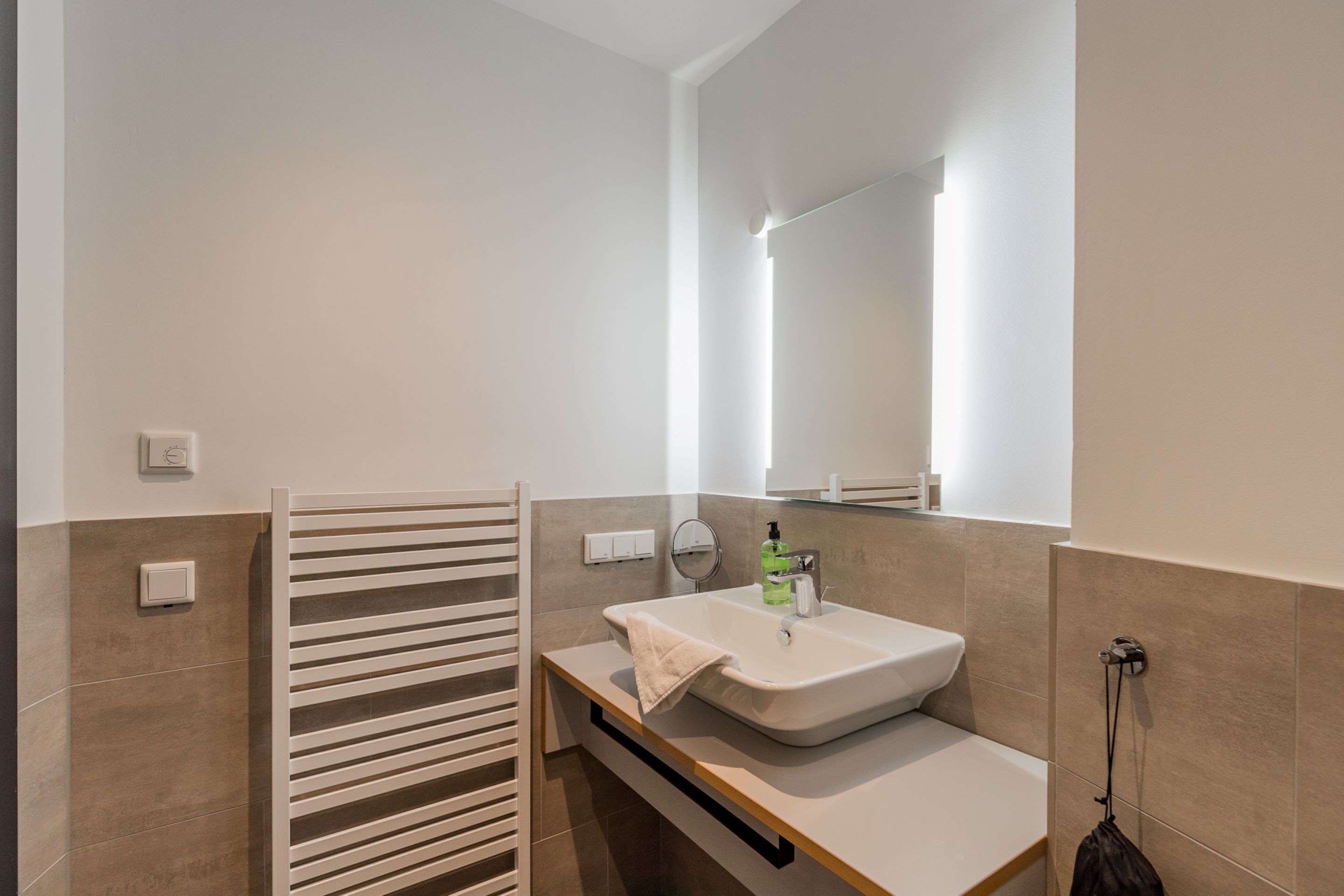 Un bagno moderno con un lavandino bianco, un portascopevoli e uno specchio.