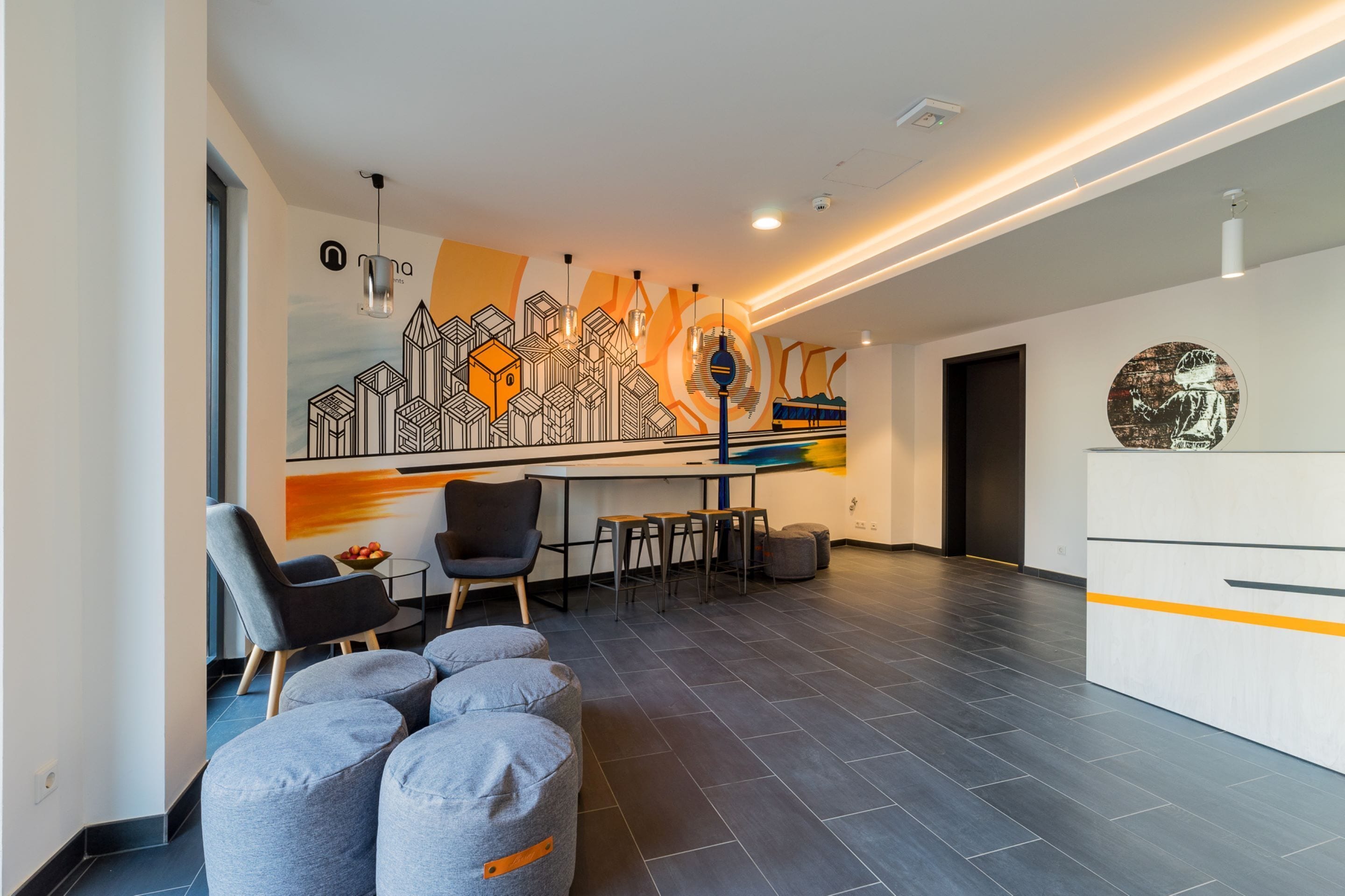 Un intérieur moderne avec un espace repas agrémenté d’une fresque murale, d’un bar et de coins salon.