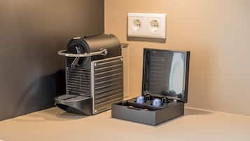 Una máquina de café con bandeja de goteo y un café recién hecho en la encimera.