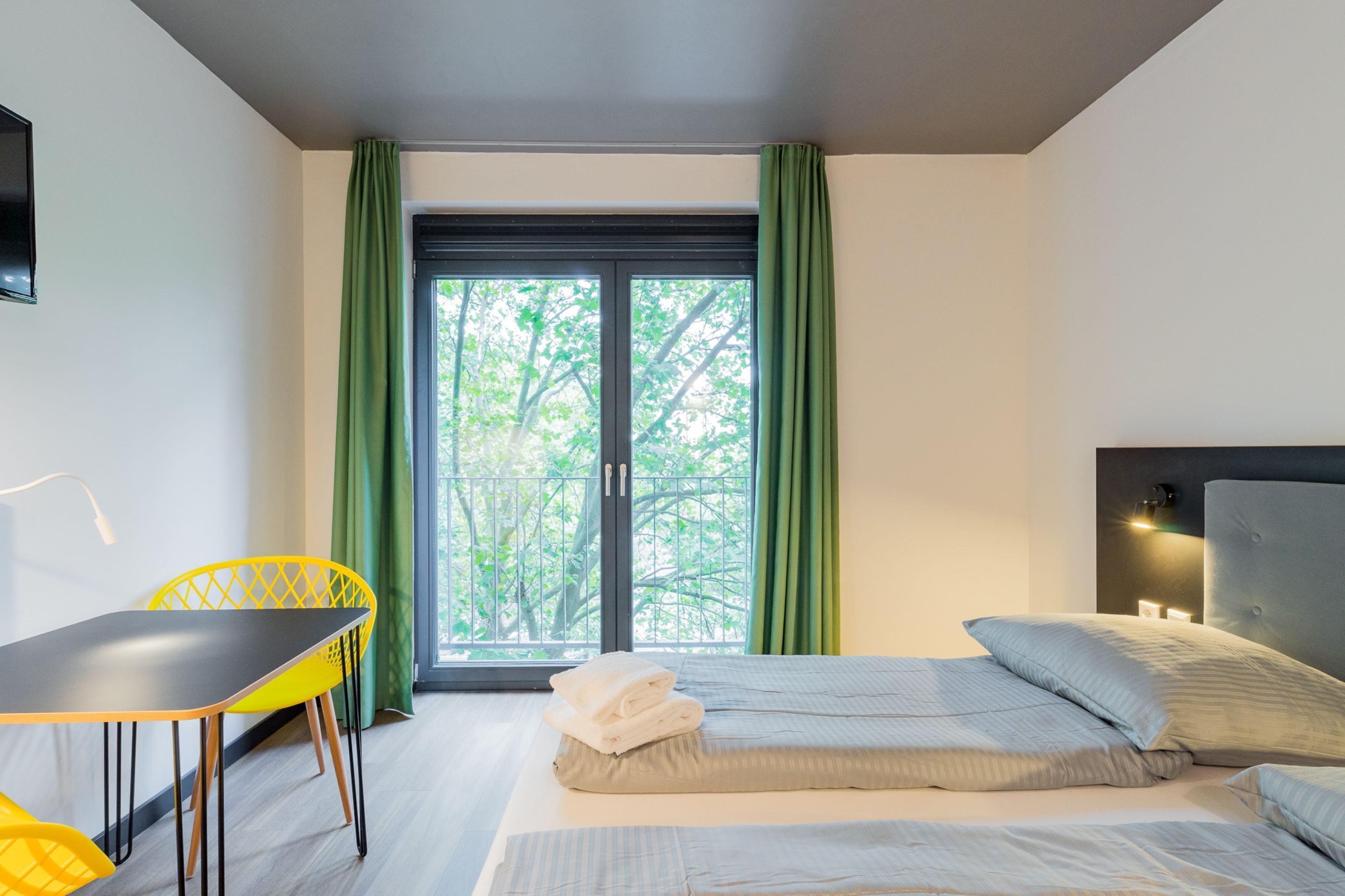 A modern hotel room with a bed, a desk, and a chair.