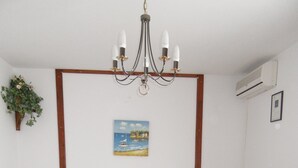 A bedroom with a wooden bed, two bedside tables, a chandelier, a painting, and an air conditioning unit. - Guest House Lidus (Gradac)