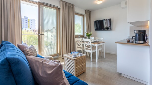 En moderne lejlighed med opholdsstue, spiseplads og tekøkken.
