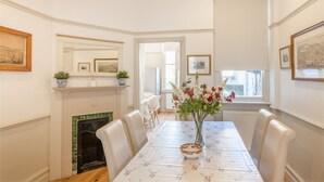 Un comedor con chimenea, paredes blancas y cuadros enmarcados.