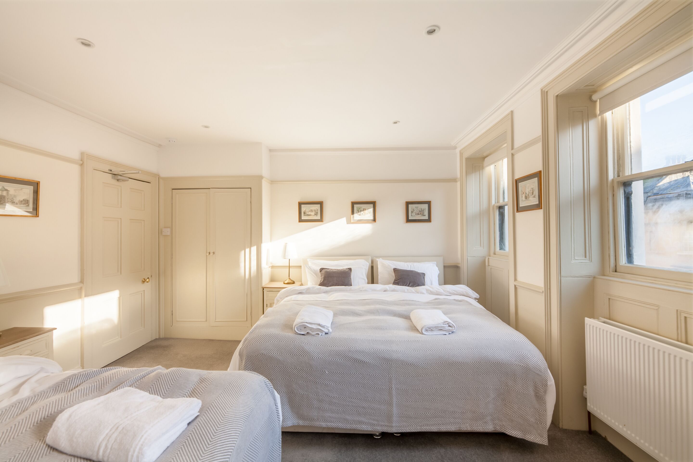 A hotel room with two beds, a large window, and a radiator.