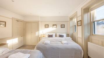 A hotel room with two beds, a large window, and a radiator.