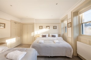 A hotel room with two beds, a large window, and a radiator.