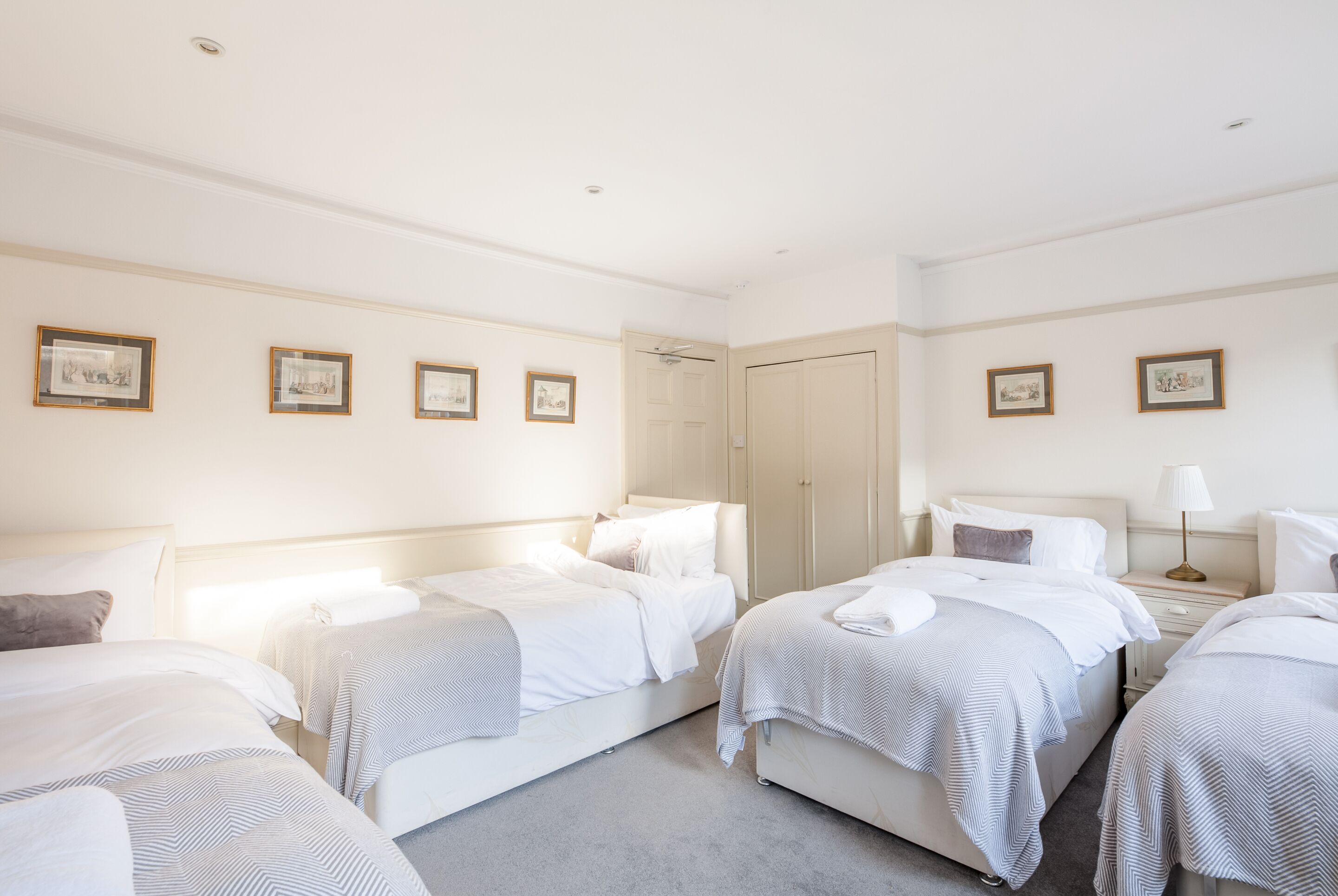 Une chambre d’hôtel avec deux lits simples, une table de chevet avec une lampe et une armoire.