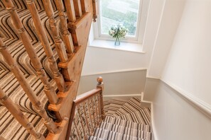 A wooden staircase with a striped carpet leading to a window with a vase of flowers. - Stunning Central Townhouse-Roman Baths- 3 min walk (Bath)