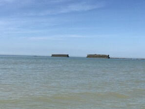 Une mer calme, avec deux grandes structures en béton visibles au loin.