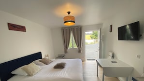 Ein Schlafzimmer mit Bett, Nachttisch und Fernseher an der Wand.