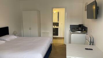 Een hotelkamer met een bed, een bureau, een stoel, een kitchenette en een kledingkast.