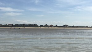 Ein Strand mit sandigem Ufer und ruhigem Wasser.