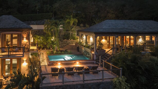 A resort with a swimming pool, outdoor seating, and a stone wall.