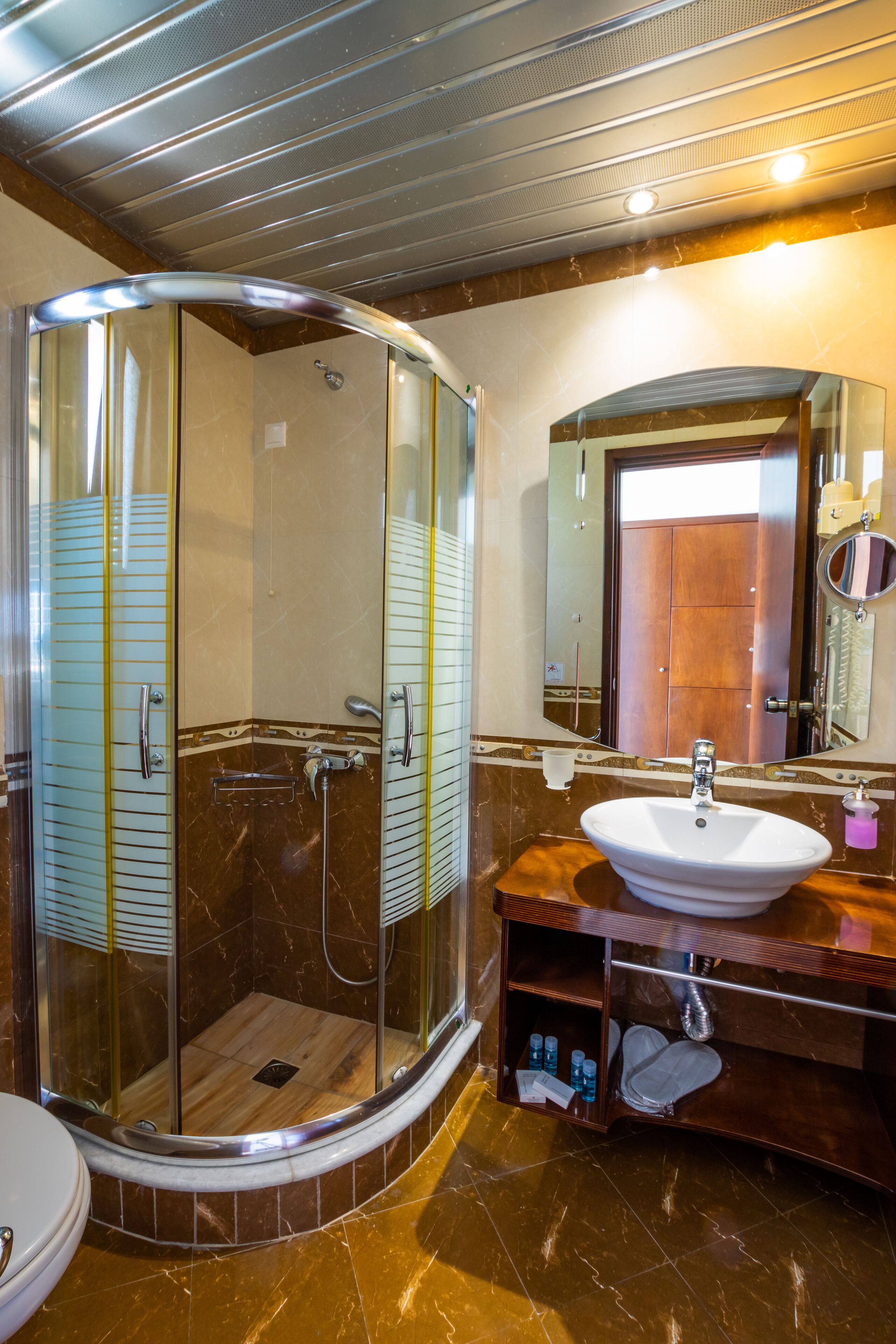 A modern bathroom with a glass-enclosed shower, a vanity with a sink, and a large mirror.