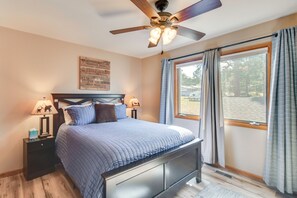 A bedroom with a bed, nightstands, a ceiling fan, a window with curtains, and a motivational quote on the wall. - Fireplace & Mtn Views: Estes Park Home w/ Deck! (Estes Park)