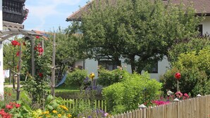 En have med træhegn, et pergola med slyngplanter og et hus med tegltag.