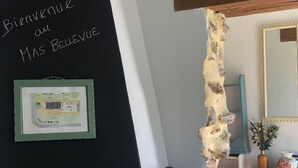 Un interior rústico con una chimenea negra, un letrero de bienvenida y un mapa enmarcado en la pared.