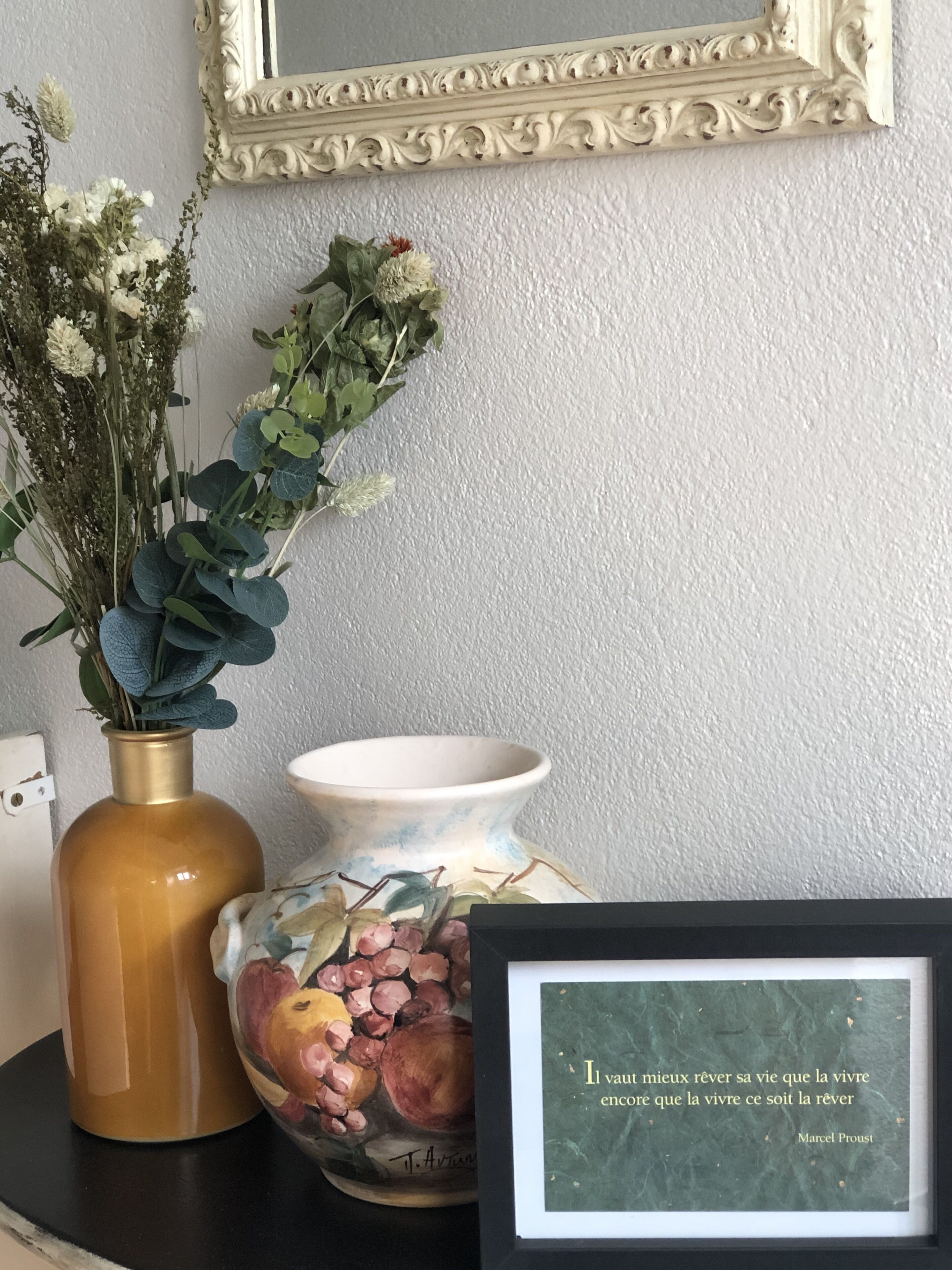 A vase with flowers, a bowl, and a framed quote on a table.