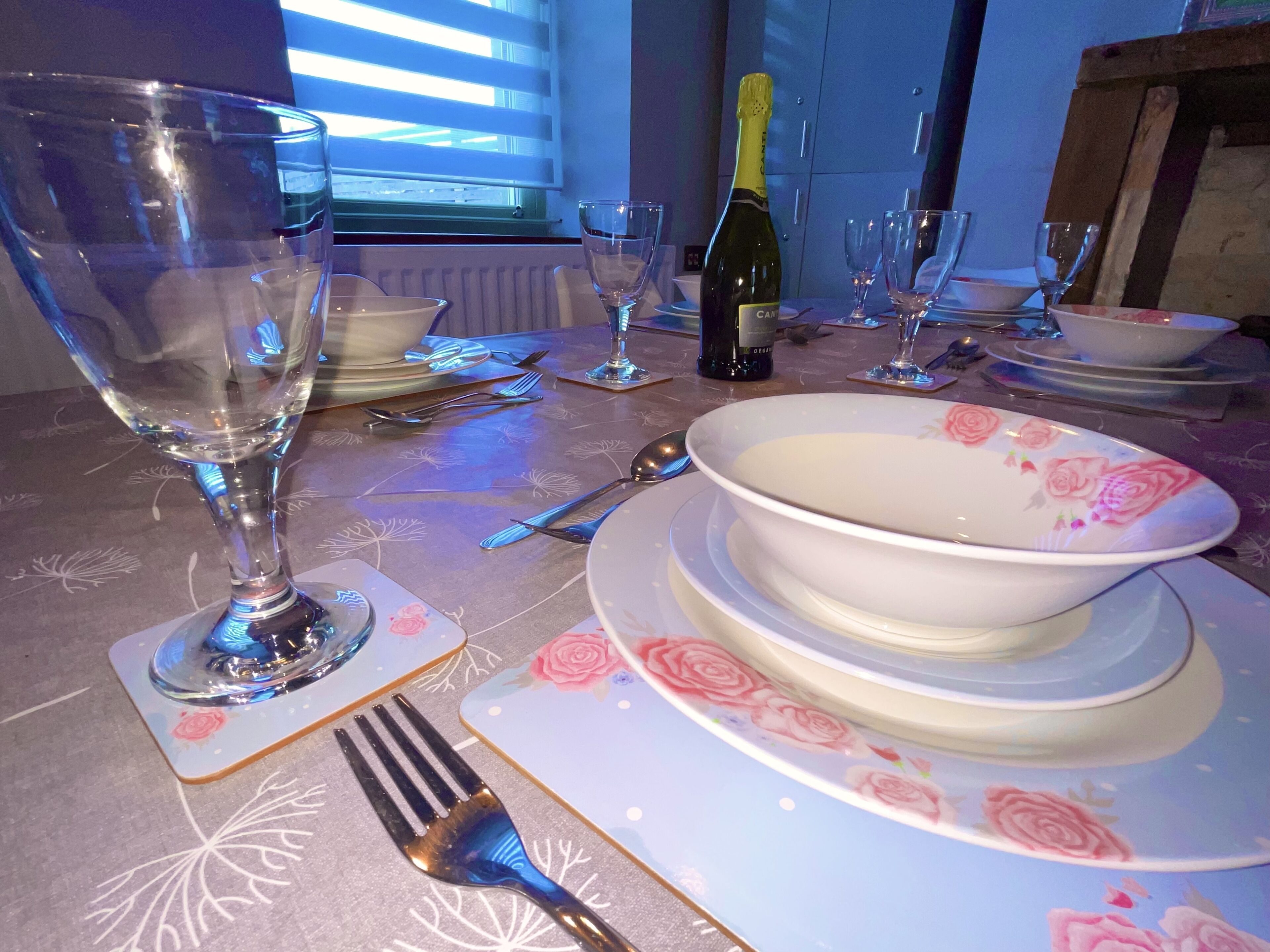A dining table set with plates, bowls, wine glasses, and cutlery.