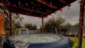 A hot tub under a wooden pergola with string lights, surrounded by a grassy area and trees. - Sleeps 8 Snowdonia North Wales Nr Zip World (Blaenau Ffestiniog)