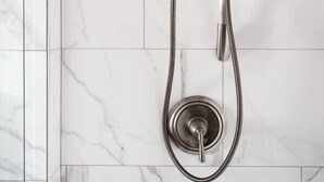 A modern shower with a handheld showerhead and a fixed showerhead, mounted on a wall with marble tiles. - Charming Suite in the Heart of Charleston (Charleston)
