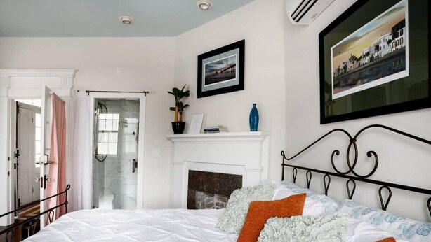 A bedroom with a bed, a fireplace, and a door leading to a bathroom. - Charming Suite in the Heart of Charleston (Charleston)