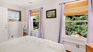 A bedroom with a bed, two windows with curtains, a door, and a wall-mounted picture. - The Gallery Suite - by MUSC ★FREE PARKING★ (Charleston)