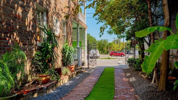 A brick building with a paved pathway and green plants. - The Gallery Suite - by MUSC ★FREE PARKING★ (Charleston)