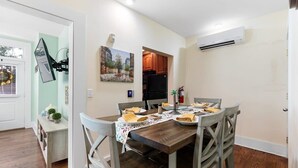A dining area with a wooden table set for four, surrounded by chairs. A painting hangs on the wall above the table. - ♥Home Too♥ in downtown Charleston, by MUSC (Charleston)