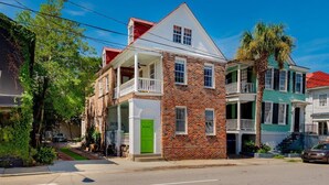 A two-story brick building with a green door, white balcony railings, and a red roof. - ♥Home Too♥ in downtown Charleston, by MUSC (Charleston)